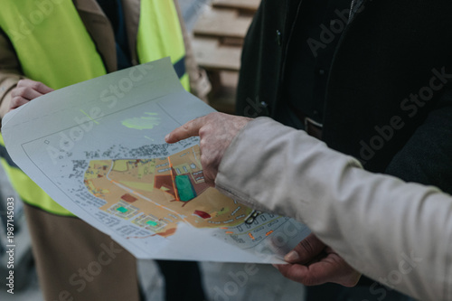 Foto Construction team members examine a printed site plan while discussing project details