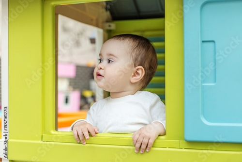 Toddler looking out of playhouse window in daycare environment