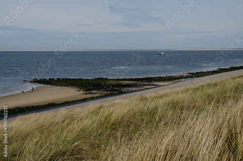 Konstfotografi High-angle view of a fishing boat sailing on the North Sea along the sandy coast and dunes of Den Helder, Netherlands