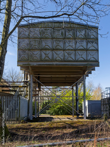 A back view of the Historical Steel Water Tanks at Stracathro Hospital Entrance, with a brick built workshop and metal railing fence.