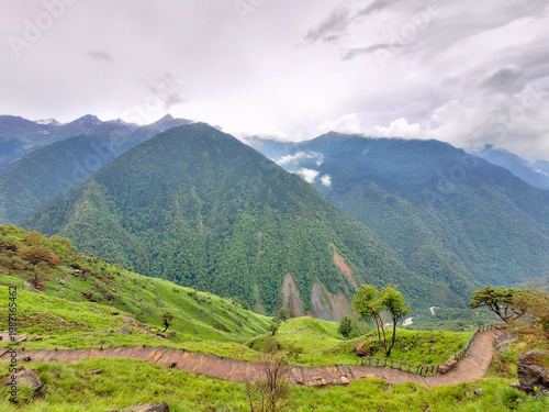 Photography A serene mountain landscape with lush green hills and trees surrounding Madmahes