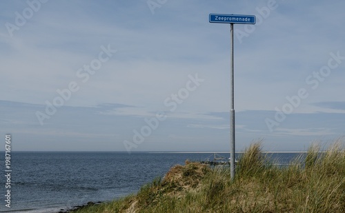 Φωτογραφία High-angle view of a Zeepromenade street sign overlooking sand dunes and a fishing vessel in the North Sea, Den Helder, Netherlands