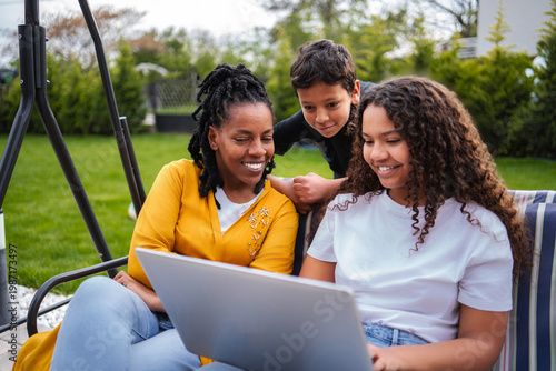 Valokuva African American family bonding outdoors enjoying laptop together