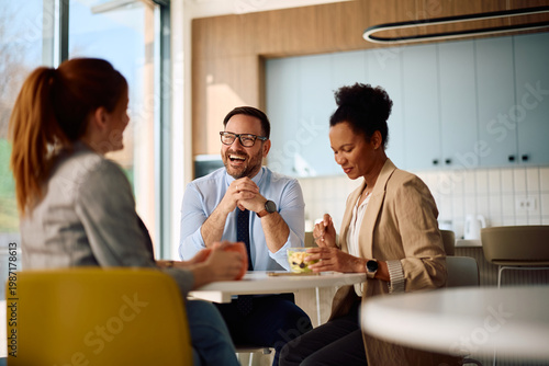 Foto Happy businessman laughing while talking to female colleagues on lunch break at work