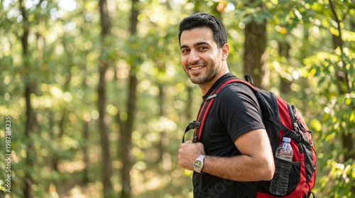 Happy young man with backpack enjoying a hike in the lush green forest during summer. Portrait of smiling male traveler walking through the woods with hiking gear and water bottle on a sunny day.