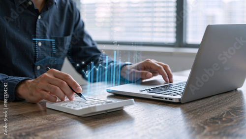 Man using calculator and laptop with financial charts