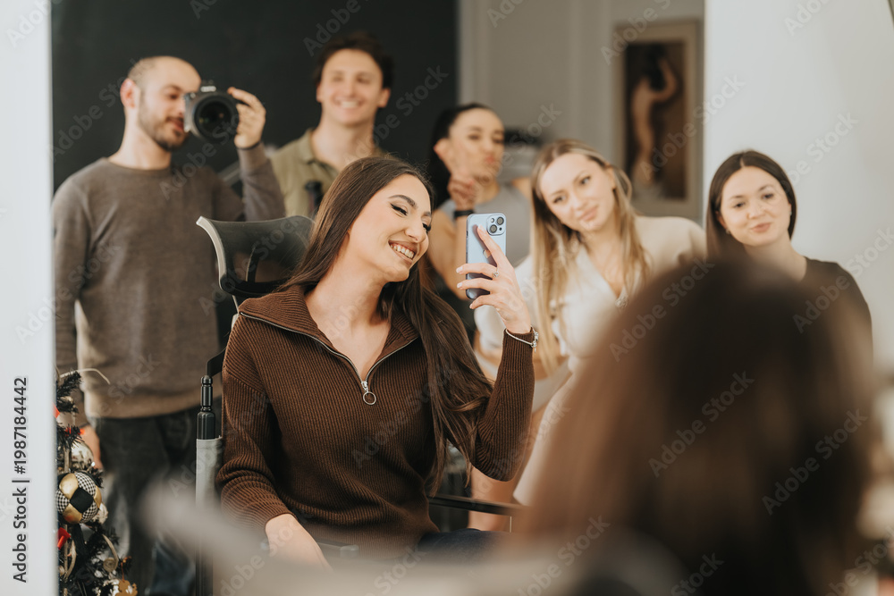 Fototapeta premium A young woman takes a mirror selfie in a beauty center while friends and a photographer look on. She smiles in a salon chair as her friends pose behind her.