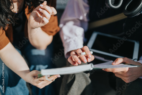 фотографія Two people review notes in a notebook while one points with a pen beside a tablet