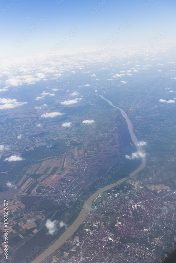 Fototapeta premium Aerial view of landscape with fields and river under scattered clouds.