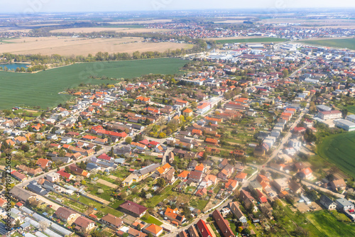 Aerial view of a suburban neighborhood with houses and gardens near green fields.