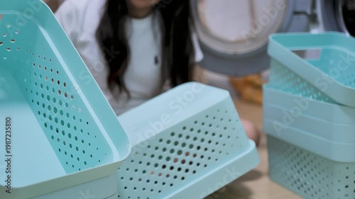 Person peeling a sticker from a plastic storage basket during home organization. The image reflects decluttering, product preparation, and everyday household routine.
