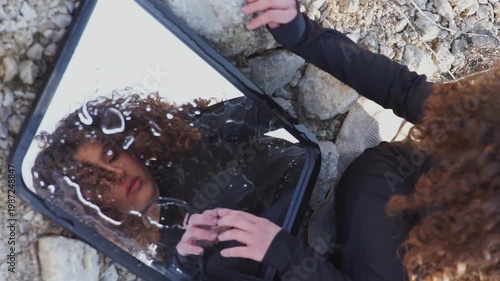 Curly haired woman touching her reflection in mirror