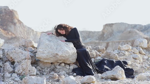 Woman in long black dress touching a rock in a quarry
