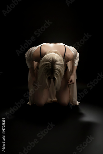 Grieving woman kneeling with head bowed in solitude