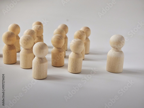 Wooden peg figures represent leadership and teamwork while showcasing the idea of standing out among a group on a plain background