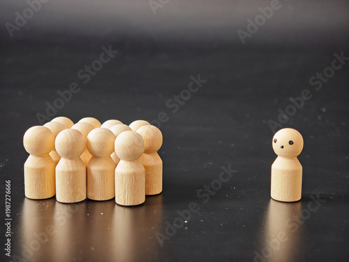 Wooden figures show individuality while standing alone against group pressure in a dark setting