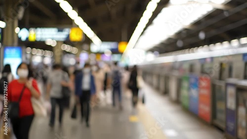 Blurred view of a busy subway station platform with people and a train.