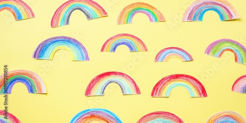 Hand drawn rainbow motifs laid out on yellow paper background