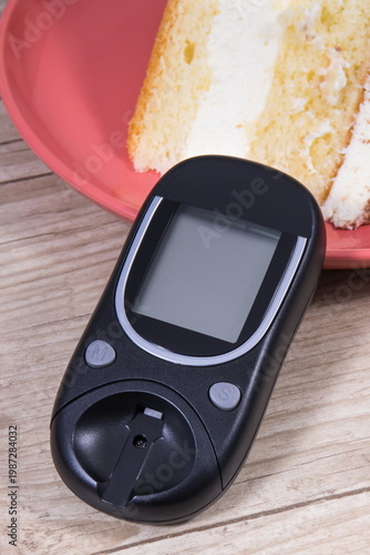 Glucose meter for measuring sugar level and piece of sweet cake with chocolate. Healthy lifestyle during diabetes