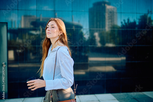 Quadro em tela Young woman walking outdoors, holding a coffee cup