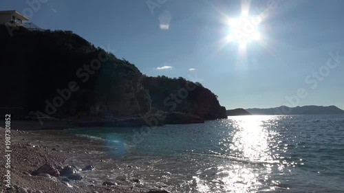 Kas, Turkey - 24 of February 2026: Beautiful seascape featuring bright sun with dark rocky cliffs under blue sky
