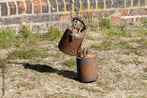 Canvas Print Rusty iron weights hanging from chain at windmill