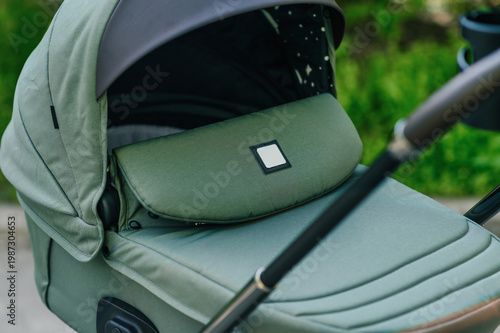 Close-up of modern baby stroller carrycot with soft fabric and canopy in green park, focus on design and materials, comfortable infant transport and premium childcare product concept