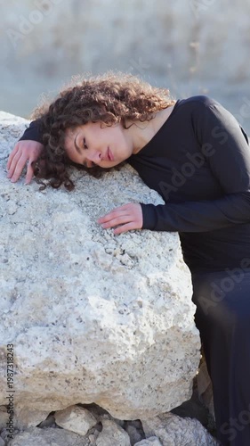 Melancholic young woman leaning on a rock