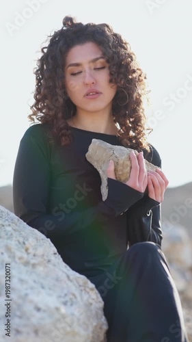 Beautiful young woman holding a rock in nature