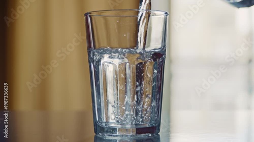 Clean transparent water being poured into a drinking glass on a table for refreshment and hydration