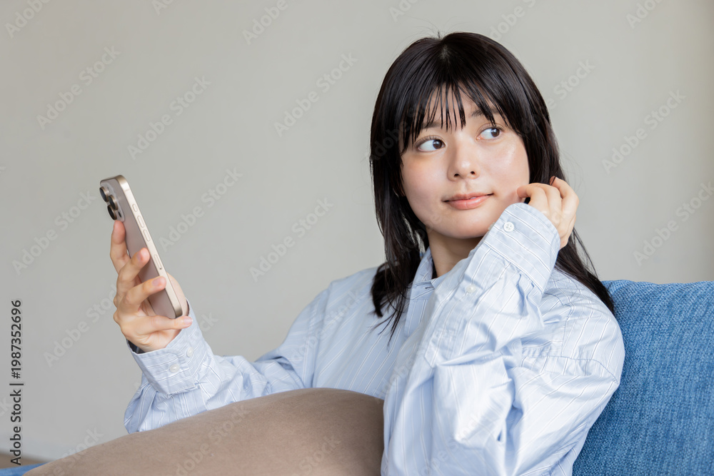 Fototapeta premium ソファに座ってスマホを操作する女性