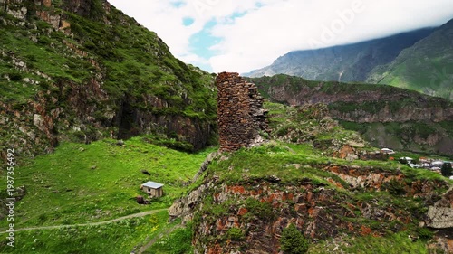 Cinematic 4K ProRes 422 aerial orbit of ancient tower ruins on a cliff. Mystical green ravine with a mountain river in Georgia.
