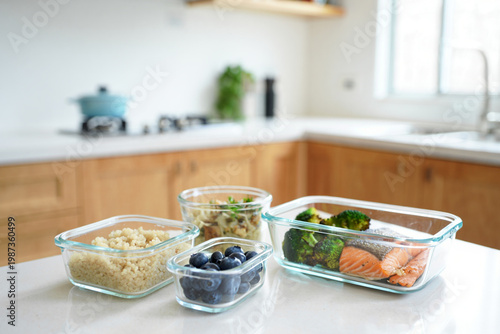 Minimalist kitchen counter with glass containers for meal prep, healthy food organization with salmon, quinoa and roasted broccoli, bright and airy atmosphere