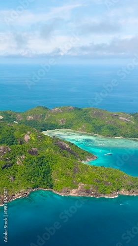 Steep hills covered in forest border the deep blue ocean, distant islands visible. Seychelles, Mahe.