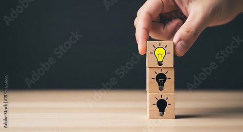 Hand stacking wooden blocks with light bulb designs symbolizing ideas and innovation