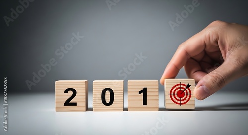 Hand turns wooden block from 201 to target symbol on gray background