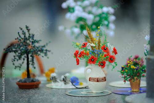Handmade beaded flower bouquet with red poppies in a ceramic vase