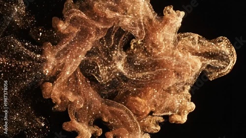 Mesmerizing swirl of golden glitter particles forming a beautiful abstract design against a black background