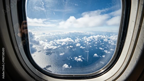 Aerial View through Aircraft Window of Fluffy Clouds and Blue Sea