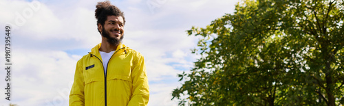 Young man in a vibrant yellow jacket embraces fitness outdoors on a sunny spring day