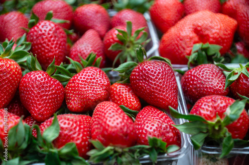 Fresh strawberries in clear plastic containers at a market during the daytime