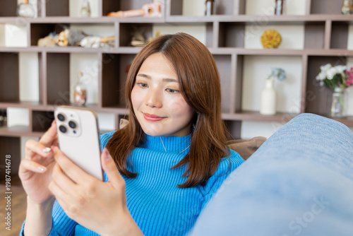 部屋でスマホを見る女性