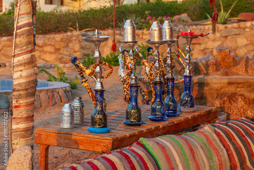Row of traditional Arabic hookahs on a wooden table at an authentic Bedouin-style lounge in Egypt.

