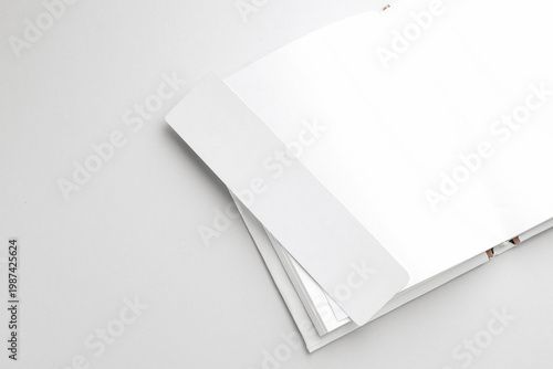 Book with white bookmark on light grey background, top view. Space for text
