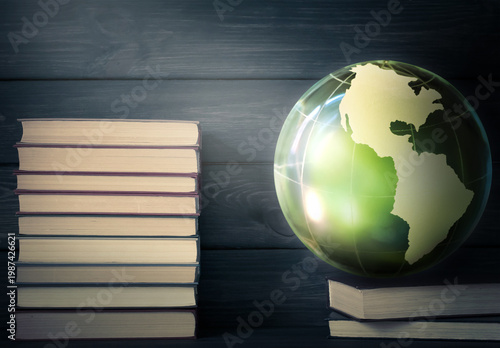 World Book Day concept with stack of paper books and Earth globe on dark wooden background. International Day of Education or reading literature theme.