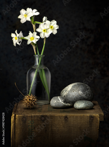 still life with flowers, rounded stones, and seed pod of sweetgum tree on old wooden box