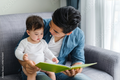 Asian young father reading storybook to daughter in living room, 