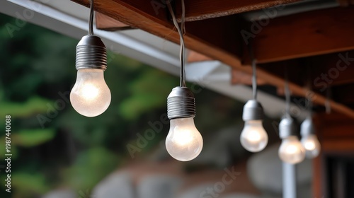 Four light bulbs hang from a wooden beam in a ceiling, casting warm light in an indoor area for brightening the space