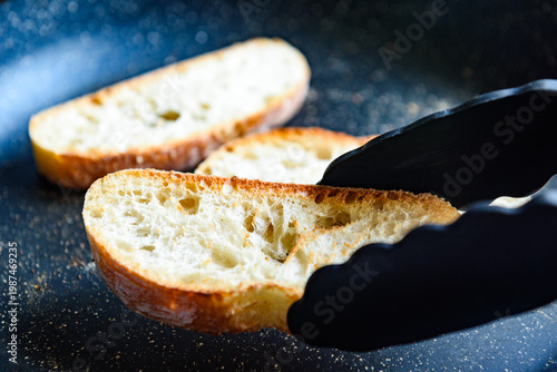 Photos Slices of wheat ciabatta cooking  on a frying pan in the morning.