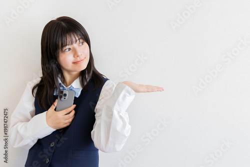 スマホを持ち手のひらで紹介する女子高校生（白背景・コピースペース）